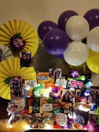 An alternate view of the glowing best friend birthday hamper, showing the arrangement of snacks, photos, and purple and yellow balloons, all brought to life with warm fairy lights.