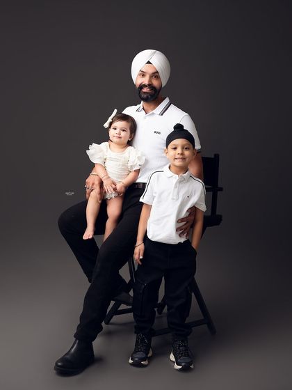 A proud father with his two children. This portrait captures the sweet dynamic between the siblings and their dad in a classic studio setting.