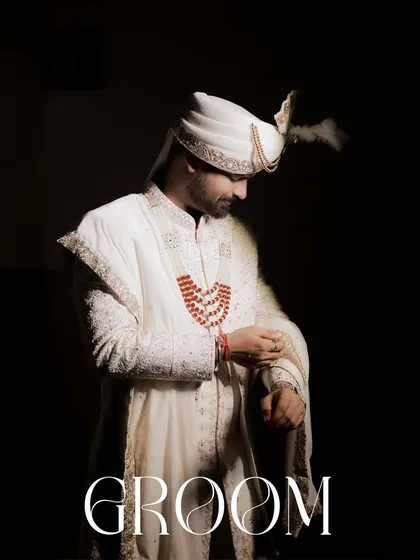 A powerful, full-length portrait of the groom against a dark background. The word 'GROOM' is elegantly overlaid, making this a definitive and timeless image from his wedding day.