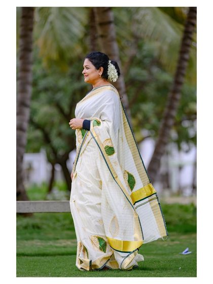 A side profile of the model in the Onam saree, highlighting the hairstyle and the fabric's texture.