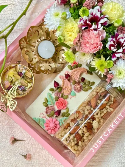 A beautiful view of my 'Festive Bloom' Diwali hamper. It includes an artisanal chocolate bar, Kesar Rose fudge, a savory mix, a lotus diya, and fresh flowers, all presented in a lovely pink tray.