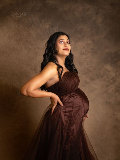 A powerful and confident pose, looking up towards the light. This shot in a rich brown tulle gown highlights the strength and beauty of the expectant mother.