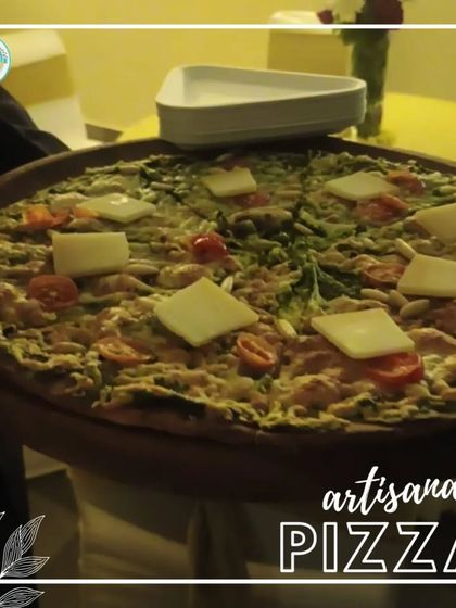 Our artisanal Pizza, served fresh at a house party. This pizza is topped with fresh vegetables and generous slices of cheese, a guaranteed crowd-pleaser.
