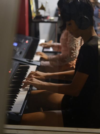 A view through the classroom window of students practicing piano. We foster an environment of shared learning and mutual support.