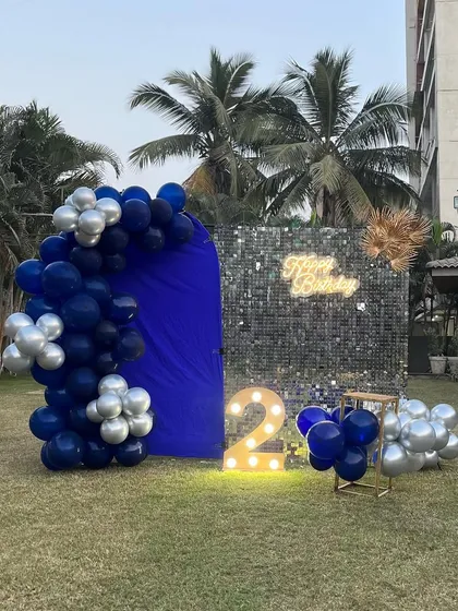 A wider view of the outdoor second birthday party on a lawn. This shows how the setup creates a stunning focal point against the backdrop of palm trees and the evening sky.