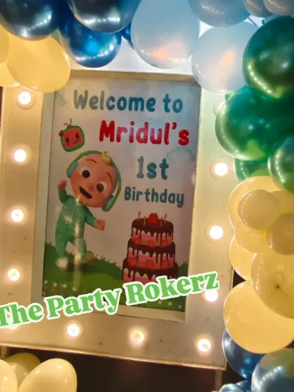 A personalized welcome sign is a great touch for any themed party. This one, for a Cocomelon first birthday, is framed with lights and a balloon garland.