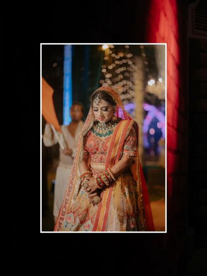 A beautiful, moody shot of Srishti during her bridal entry, the dark background making her colorful lehenga stand out.