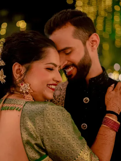The purest joy is found in these unscripted moments. A close-up of a couple sharing a genuine, happy smile, their connection illuminated by the soft glow of celebration lights.