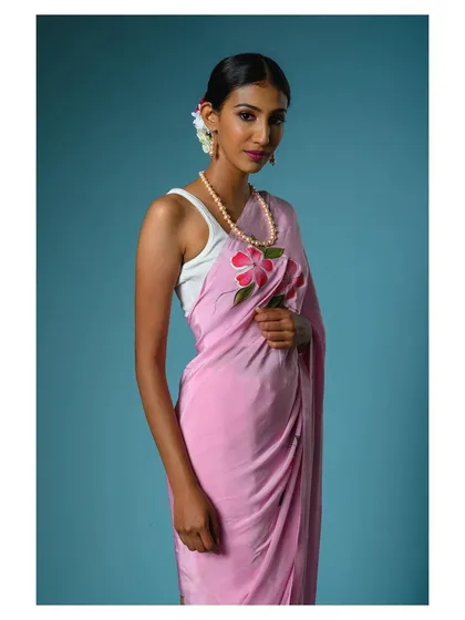 A close-up portrait focusing on the model's serene expression and the delicate floral details on the pink saree.