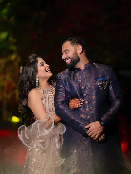 A candid moment of laughter and joy from a reception party, with the couple looking radiant in their evening wear.