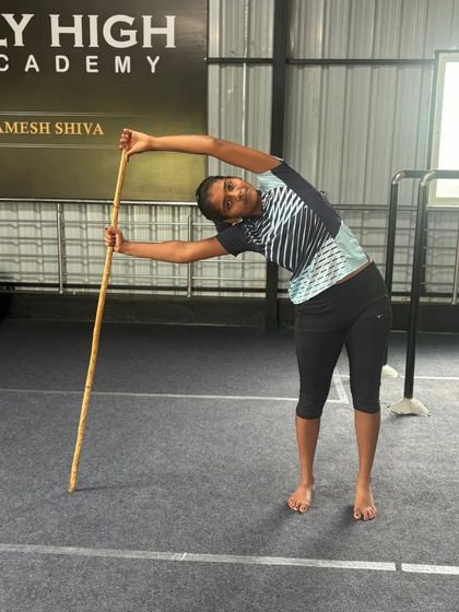 Using a stick for support, this student works on her side bend, improving core strength and mobility.