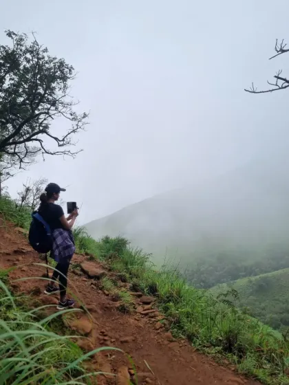 Capturing the memory. A trekker stops to take a photo of the misty valleys on the Nethravathi trail. The views are picture perfect.