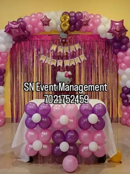 A cute Hello Kitty theme for an 8th birthday. This home setup includes a balloon arch, themed pillars, and a matching table decoration, all in pink, purple, and white.