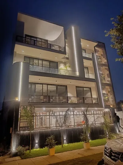 At night, architectural lighting transforms this modern residence. We used vertical light strips to emphasize the curved structural elements and uplighting to highlight the textured surfaces, creating a dramatic and sophisticated presence after dark.