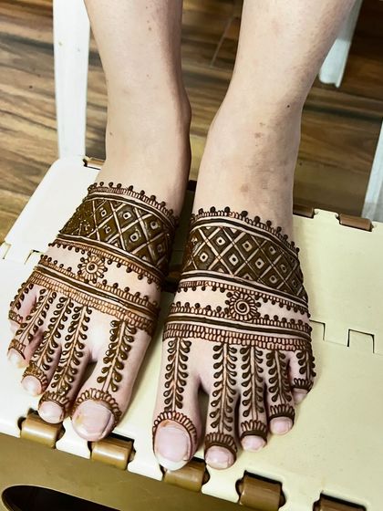 A simple yet elegant foot mehendi design. The pattern features leafy vines on the toes and a delicate band across the top of the foot.