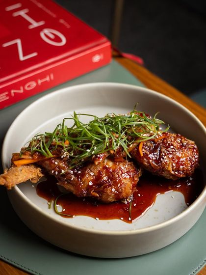 An unforgettable classic you'll want to order every time. These are our shrimp-stuffed chicken wings, glazed in a sticky gochujang sauce and brightened with kimchi and fresh scallions.