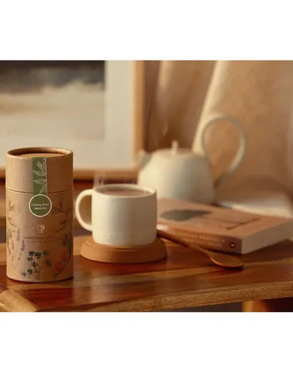 Creating a cozy, aspirational moment with a cup of hot tea, a good book, and beautiful packaging. This lifestyle branding image connects the product with feelings of comfort, relaxation, and self-care.