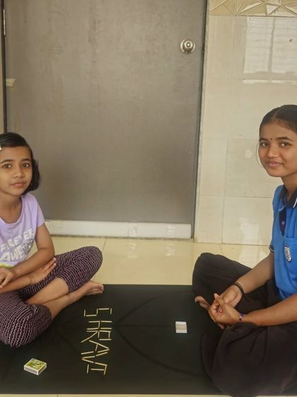 Mindful activities are a core part of our kids' yoga sessions. Here, two children are engaged in an art activity using matchsticks to create their names on a yoga mat. This exercise helps improve their concentration and fine motor skills in a calm, creative setting.