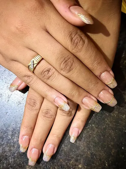 A beautiful set of long, square-tipped extensions with a sheer glitter base and a delicate, wavy gold line near the tip.
