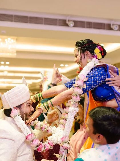 A fun and chaotic moment during the 'varmala' exchange, with the bride and groom lifted up by their families.