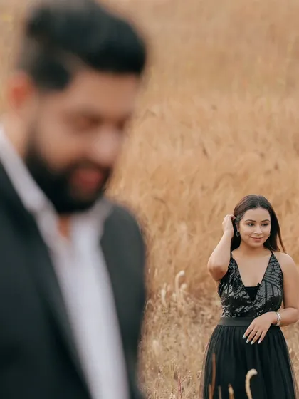 An artistic shot using depth of field, with the groom in the blurred foreground and the bride looking elegant in the background.