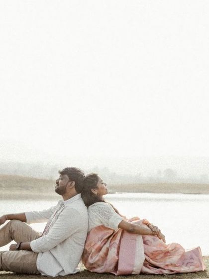 A peaceful moment of the couple resting back-to-back by the lake, enjoying the quiet and serene landscape.