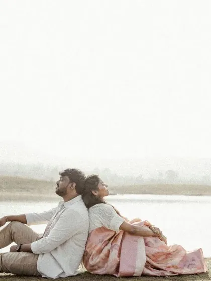 A peaceful moment of the couple resting back-to-back by the lake, enjoying the quiet and serene landscape.