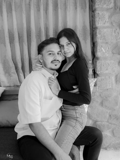 A direct and engaging black and white portrait. The couple looks towards the camera, their embrace conveying a sense of confident and comfortable love.