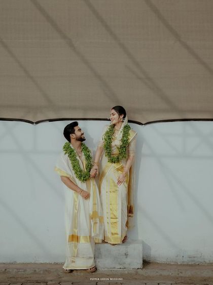 A stylish portrait of the couple after their Guruvayur temple wedding, their traditional attire looking elegant against a simple white wall.