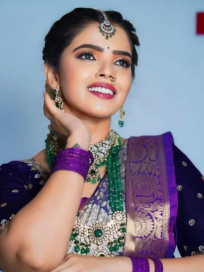 This model is wearing a beautiful Victorian set with green beads and a matching maang tikka. The purple saree and green jewellery create a striking contrast.