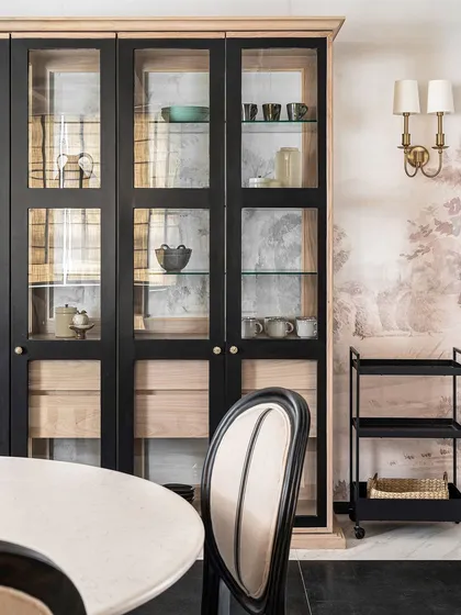 The custom cabinetry in the Riviera Maison dining area provides ample storage while serving as a beautiful display for ceramics and glassware. The brass wall sconce adds a touch of warmth.