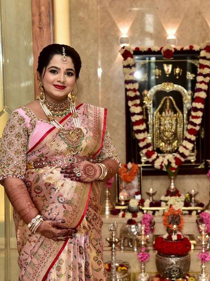 A mom-to-be standing before the family shrine during her Seemantha ceremony. Her beautiful mehendi is an integral part of her traditional attire for this blessed event.