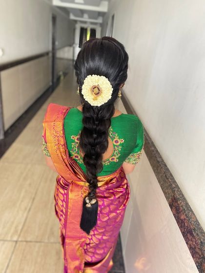 A classic South Indian braid (jadai) decorated with fresh flowers and a traditional hair accessory. This style is perfect for silk sarees.