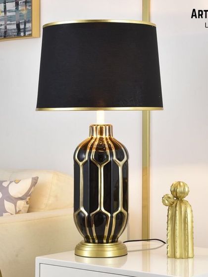 Modernity and craft combine in this ceramic table lamp. The base features a hand-painted reactive glaze in black and gold, creating a geometric pattern that gives your decor a fresh, contemporary look.