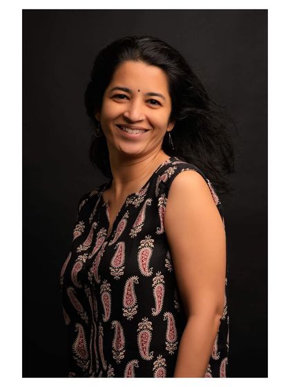 A simple and honest portrait of a woman with a genuine smile. The black background and natural expression make this a timeless headshot.