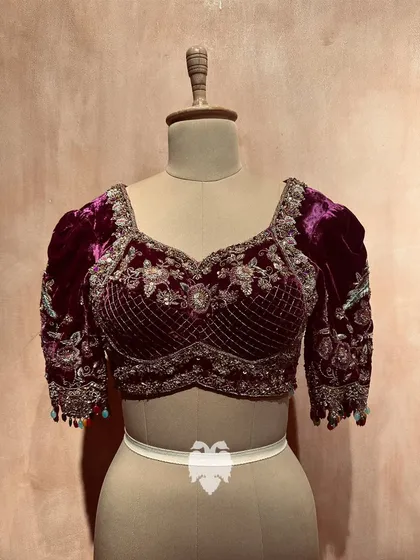 I believe in the royal touch of velvet. This plush purple blouse is a testament to that, featuring Pichwai-inspired motifs on puff sleeves and a bust patterned in regal checks. The design is a rich tapestry of zardosi, sequins, and beads, blending heritage with opulence.