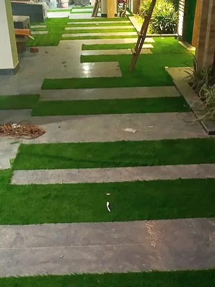 An in-progress shot of a modern walkway installation. I created a pattern by laying strips of artificial grass between large grey stone tiles, resulting in a contemporary and graphic look.