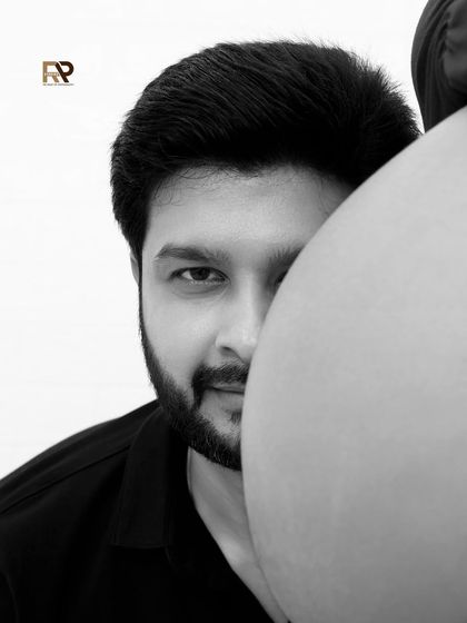 A creative and artistic black and white portrait. The father-to-be's face is partially hidden by the baby bump, creating a unique and intriguing composition that speaks to his anticipation.