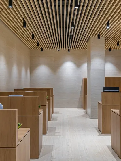 This perspective highlights the spacious layout and the effect of the lighting design. Spotlights are strategically placed to illuminate the workstations and the textured walls, creating a bright yet comfortable environment.