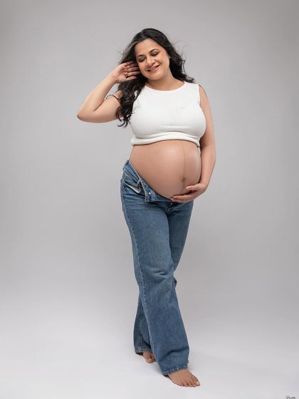 A casual and carefree look with a white crop top and unbuttoned jeans. This style is relaxed, authentic, and beautifully showcases the bare bump.