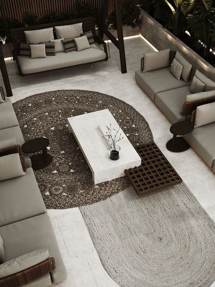 An overhead view of a spacious rooftop lounge. The layout includes multiple seating zones, a central coffee table, and a mix of circular and rectangular rugs to define the areas.