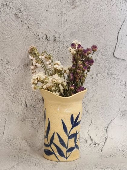 This unique, hand-painted vase with an altered rim is a perfect addition to any home. It's a small, delicate, modern-looking vase, great for holding dried flowers.