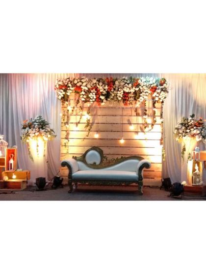 We love creating rustic yet elegant themes. This stage uses a wooden panel backdrop, warm Edison bulbs, and lush floral arrangements to create a cozy and stylish atmosphere perfect for a reception or engagement party.
