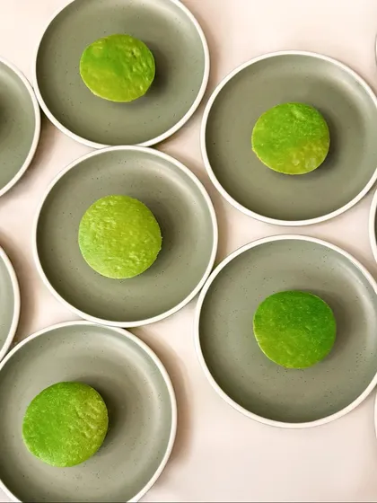 A vibrant green dish served on a muted grey plate, another creation inspired by the color palette of Annie Morris's sculptures. The composition is minimalist, allowing the color to be the hero.