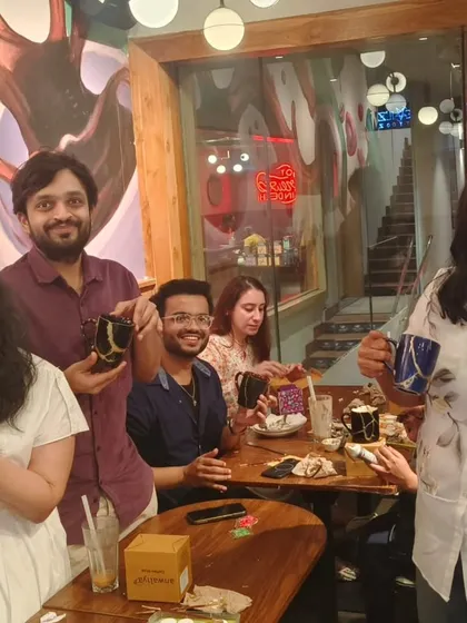 A group proudly displays their finished Kintsugi mugs. Each piece is unique, telling a different story of breakage and repair.