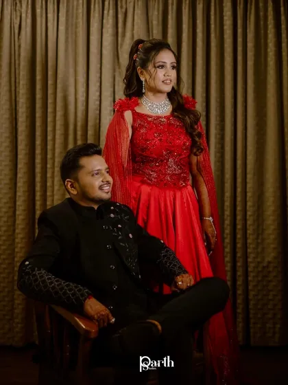 A powerful and regal couple portrait from their sangeet. The bride's red gown with a cape is a showstopper.