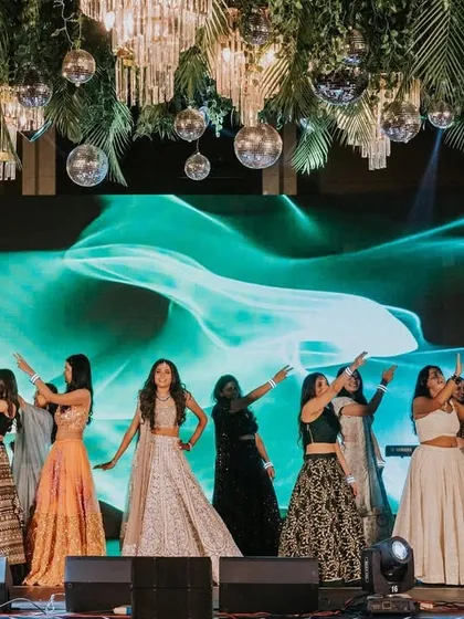 Always with her bridesmaids. This shot captures the power and unity of the bride's squad as they perform a synchronized routine under a stunning ceiling of disco balls and florals.