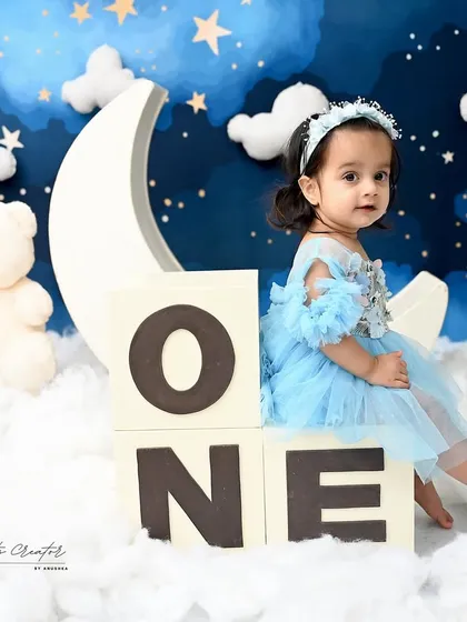 Sitting on "ONE" blocks in a starry night sky. This creative setup is a beautiful way to announce a first birthday milestone.