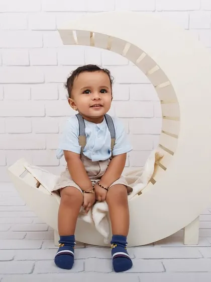A calm and sweet portrait of a one-year-old boy on a white moon prop.
