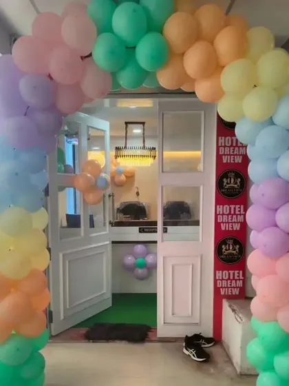 A welcoming pastel rainbow balloon arch at the entrance of a hotel or party venue for an event.